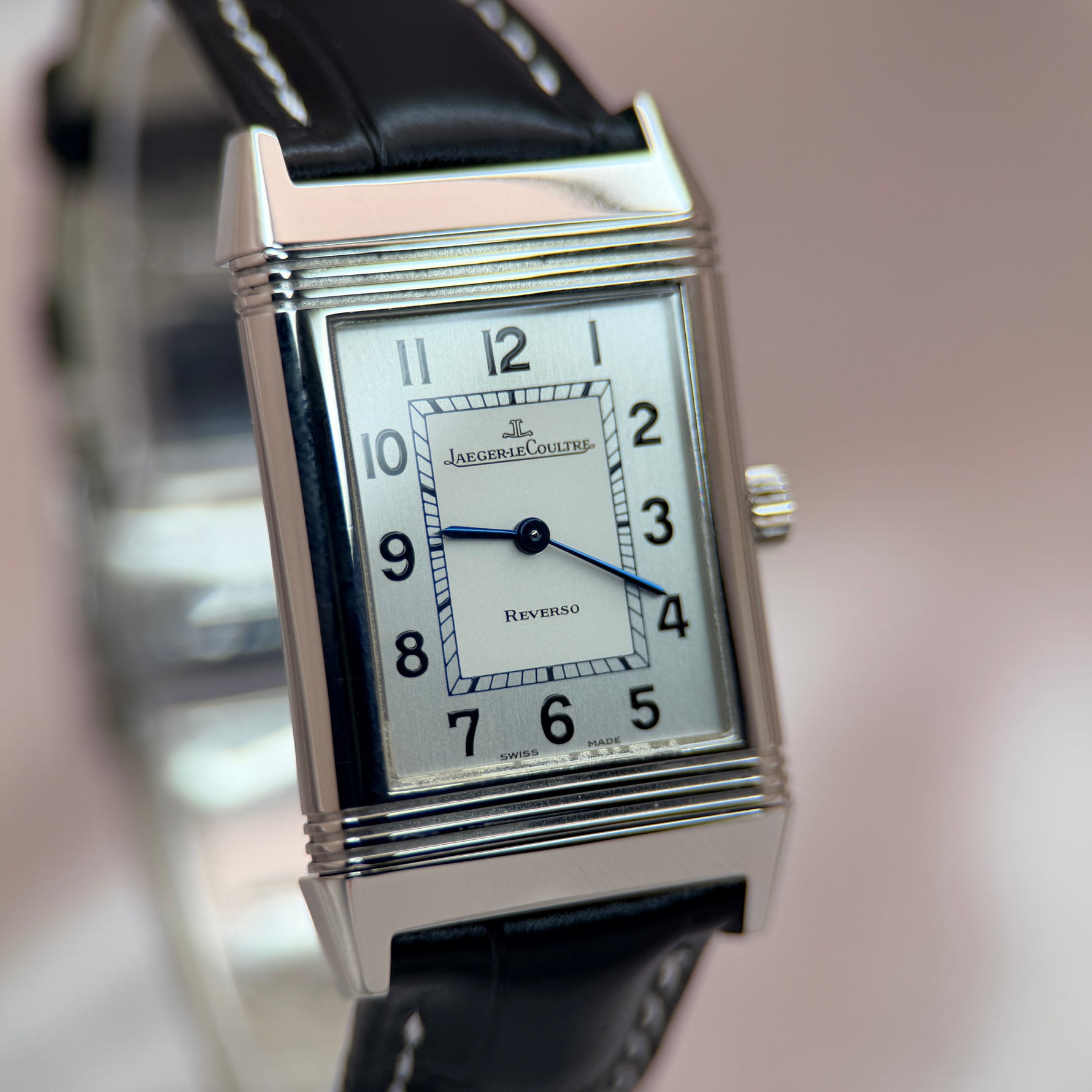 Jaeger-LeCoultre Reverso close-up dial view, cream silvered dial with blue steel hands and Arabic numerals, stainless steel rectangular case, black leather strap