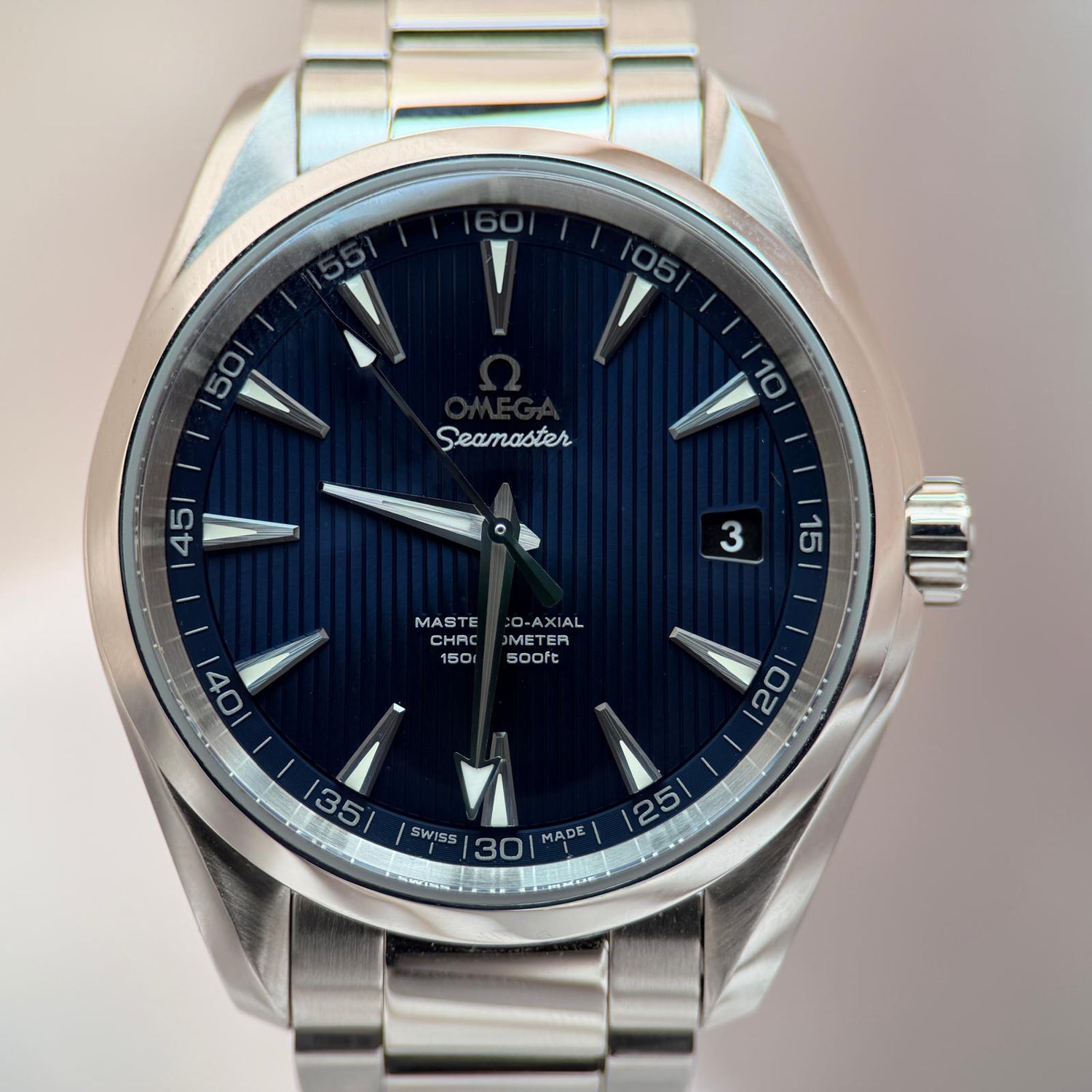 Omega Seamaster watch with blue dial and silver metal strap on a light background