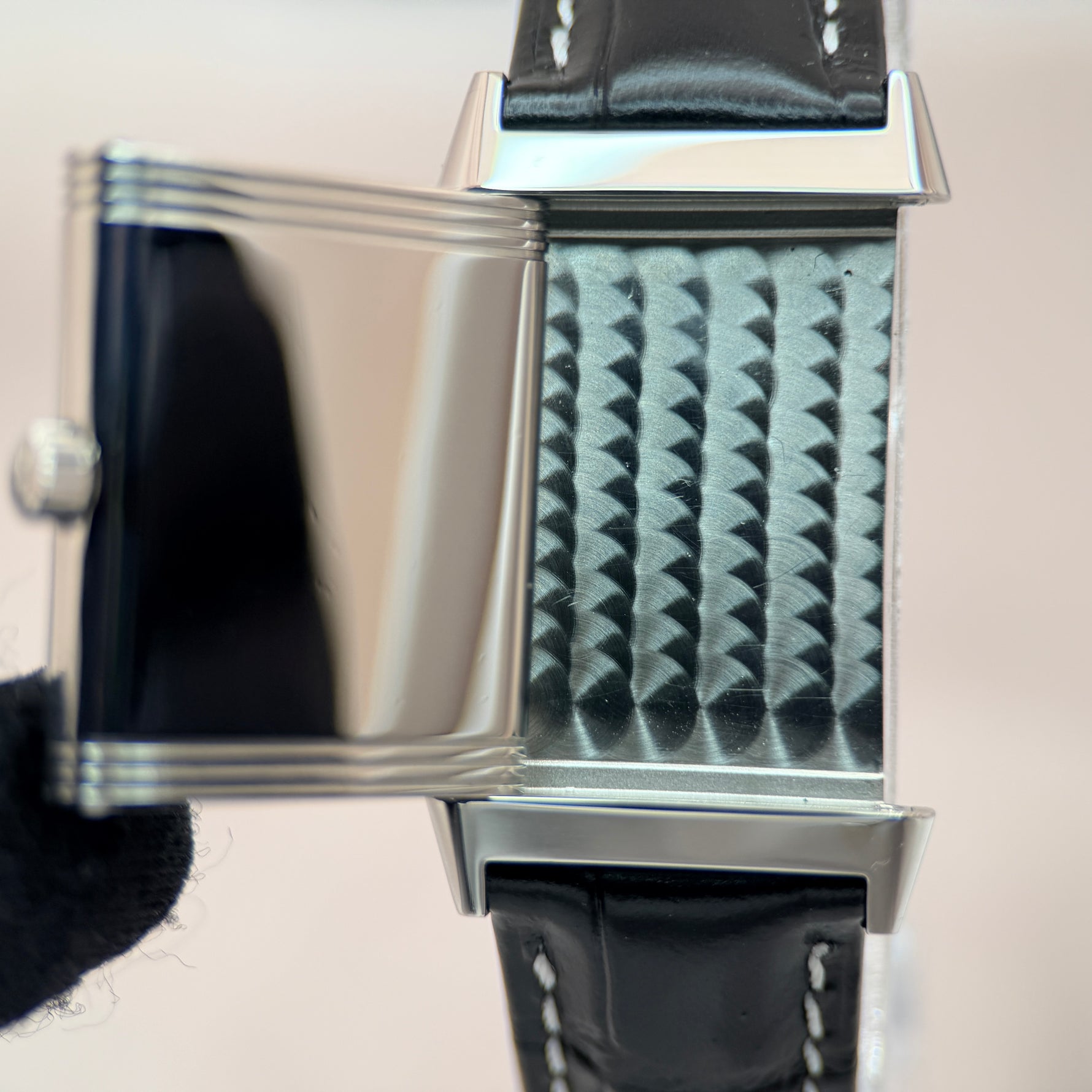 Jaeger-LeCoultre Reverso back panel close-up showing decorative Clous de Paris guilloché texture, stainless steel case with black leather strap