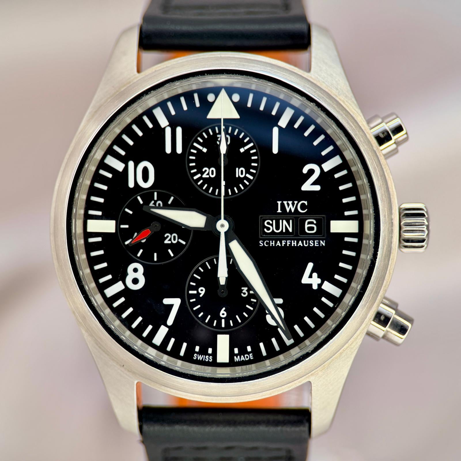 IWC watch with black dial and leather strap on a blurred background