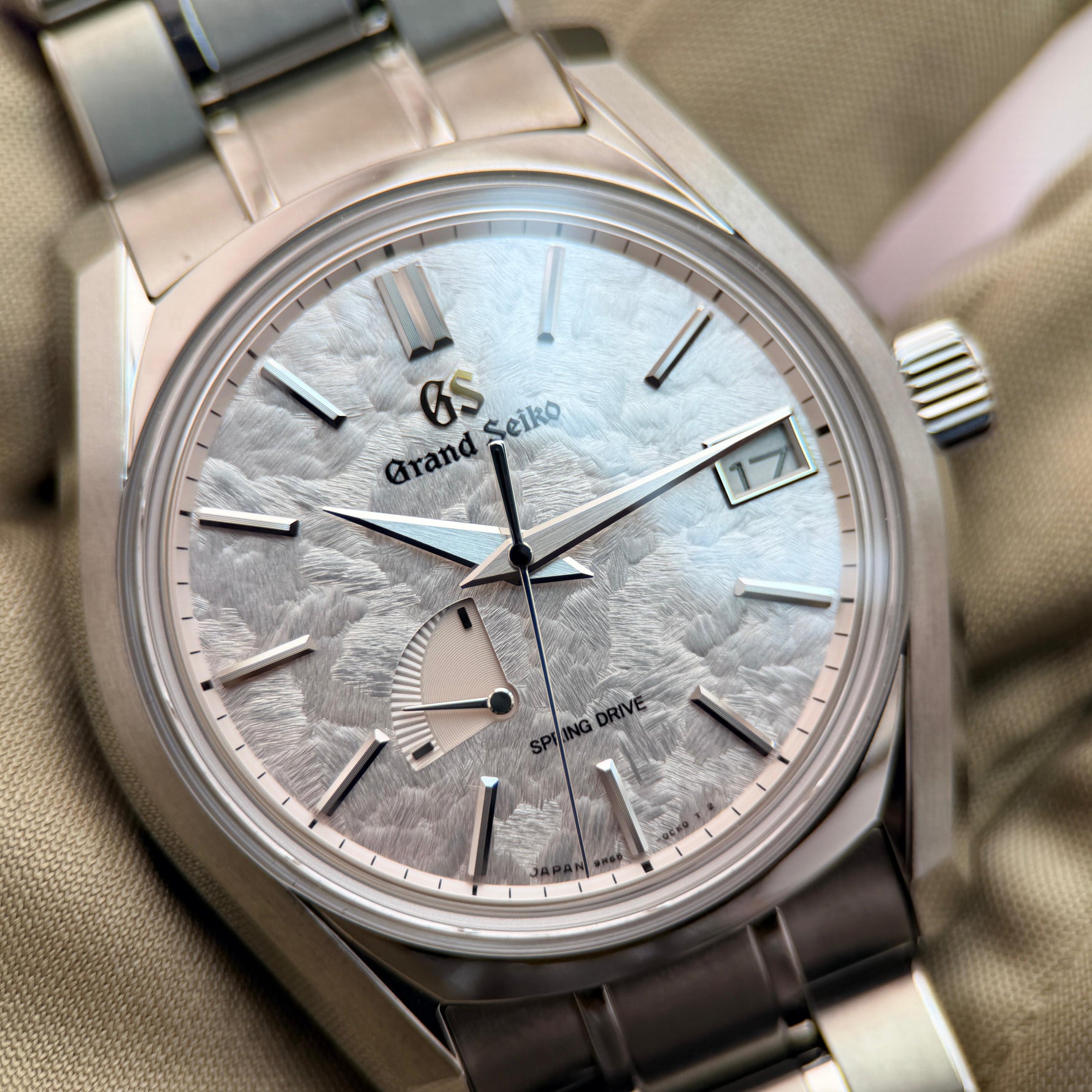 Grand Seiko watch with detailed face and brand logo on a beige background